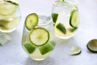 Glasses of Pineapple Green Caipirinha with lime wheels lining the inside of the glass.