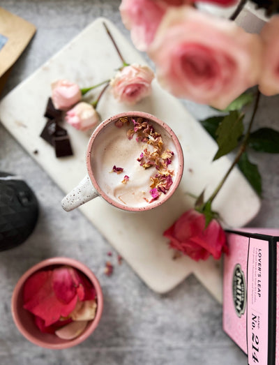 Lover's Leap Hot chocolate on a cutting board surrounded by roses and a pink box of Lover's Leap tea.