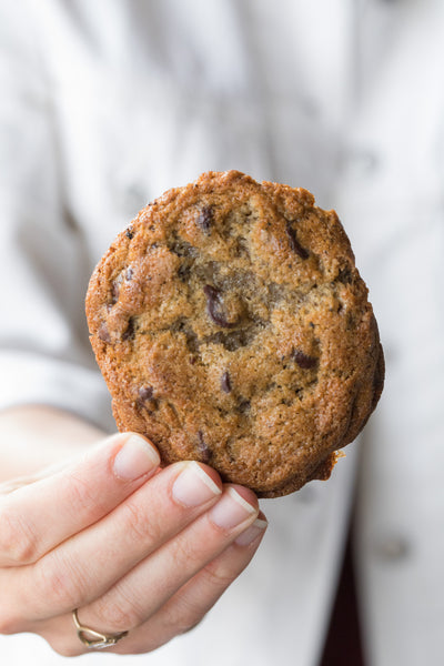 Hand holding up a large Masala Chai Chocolate Chip Cookie.