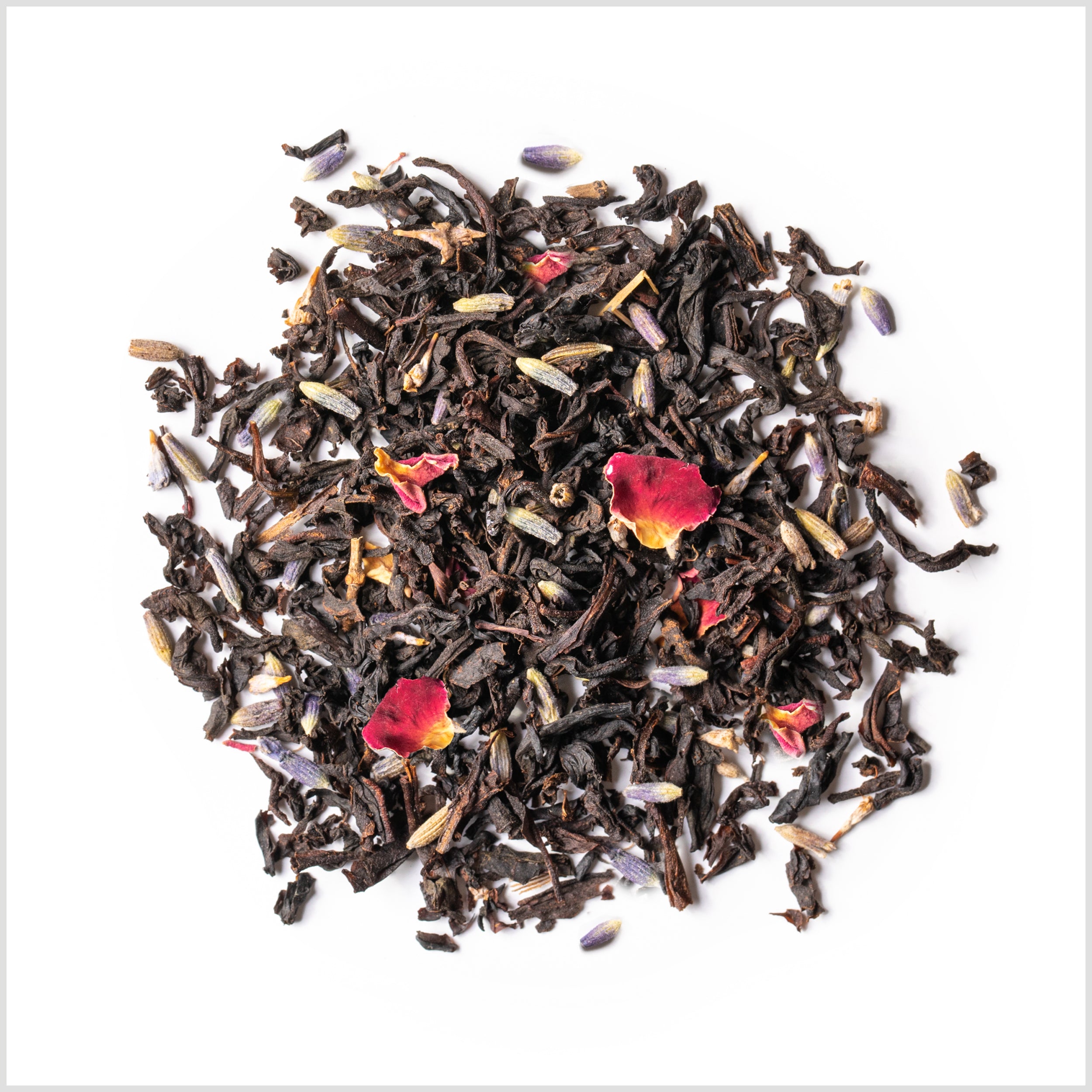 Circular pile of loose-leaf black tea with lavender and red rose petals.