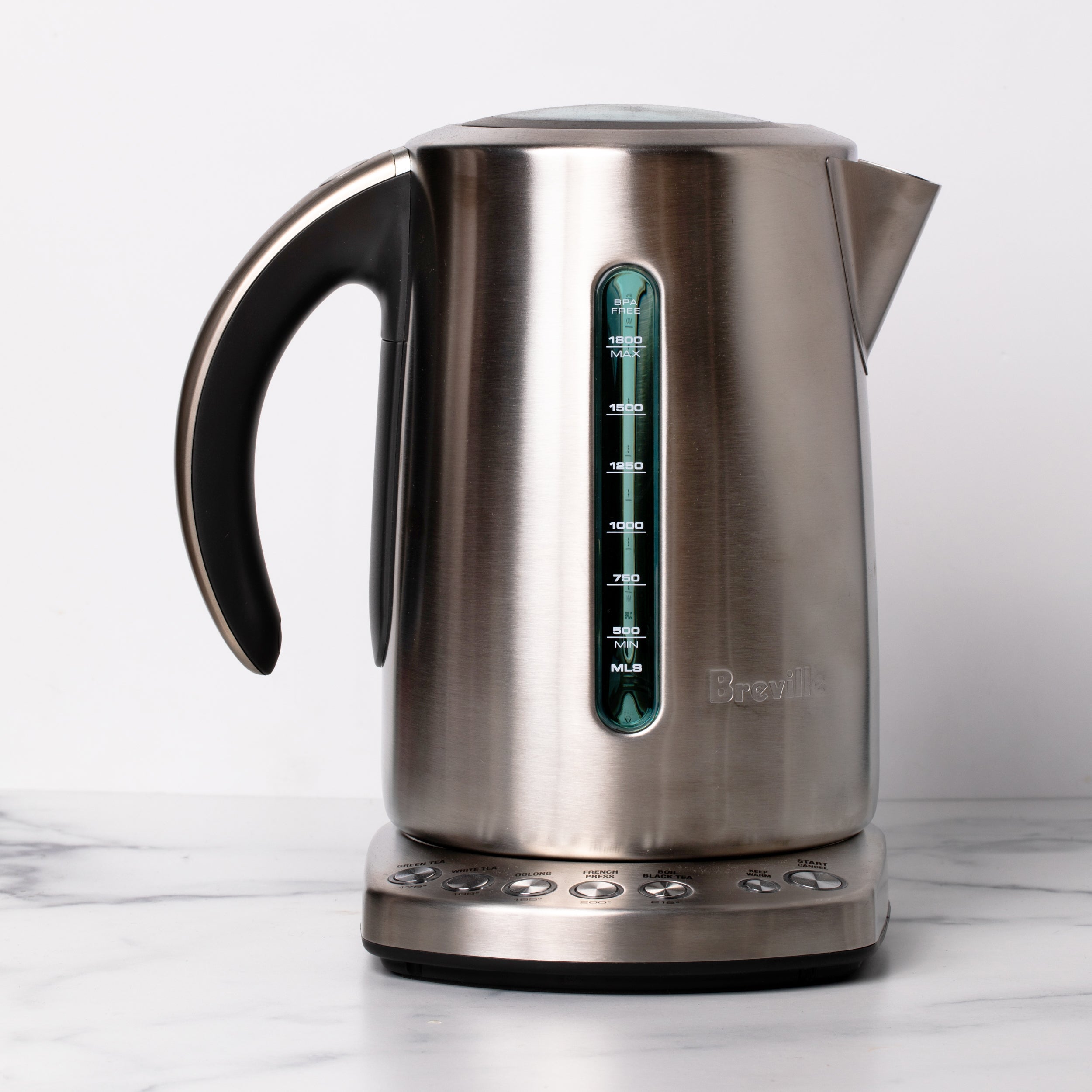 Stainless steel kettle with spout and handle on an electric base.