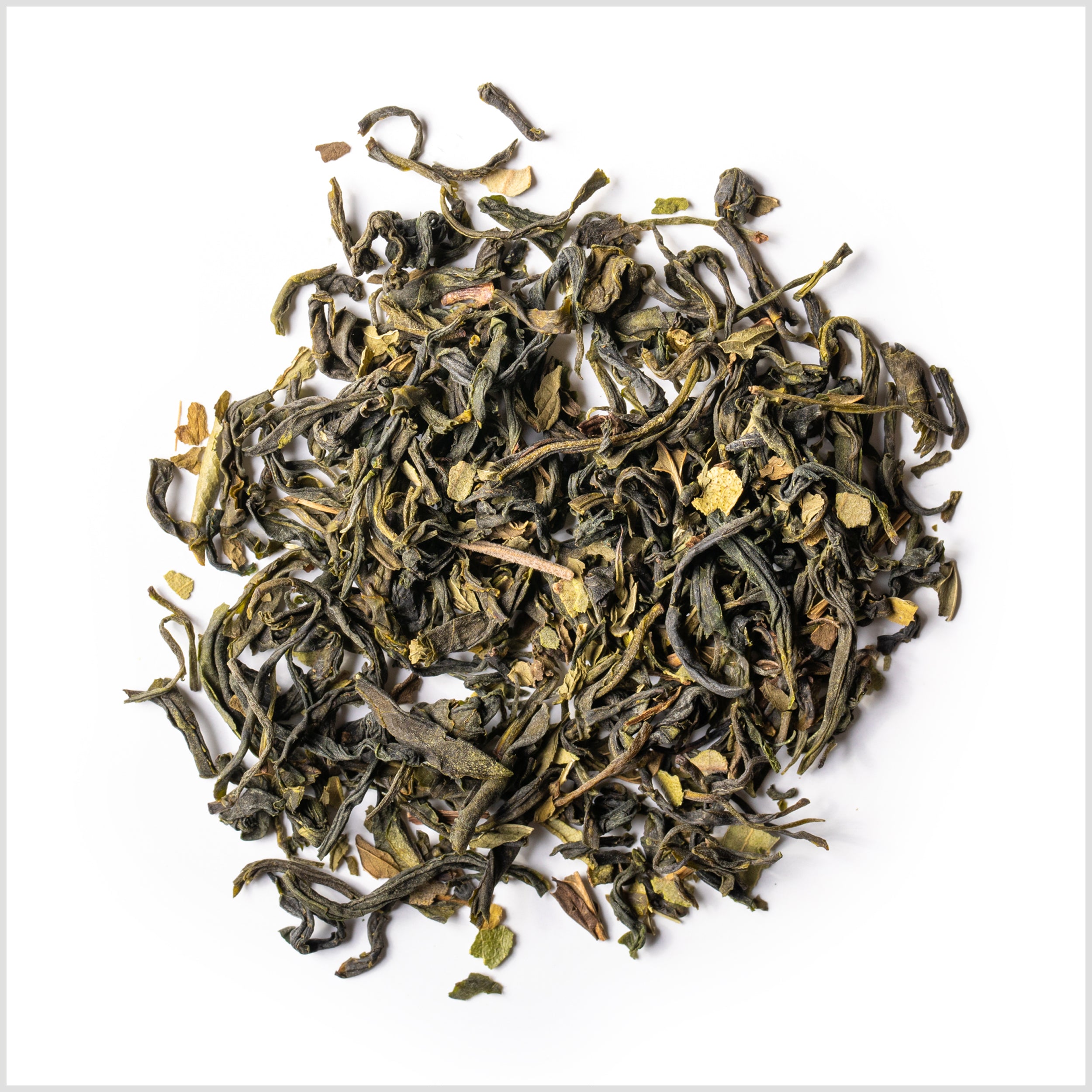 Circular pile of full leaf green tea with pieces of peppermint on white background.