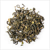 Circular pile of full leaf green tea with pieces of peppermint on white background.