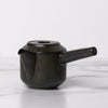 Black lidded teapot with spout and long handle.