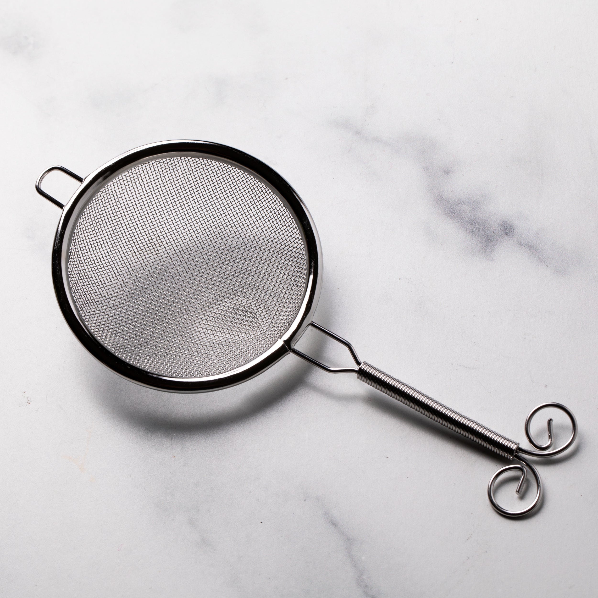 Round stainless steel sifter with a handle.