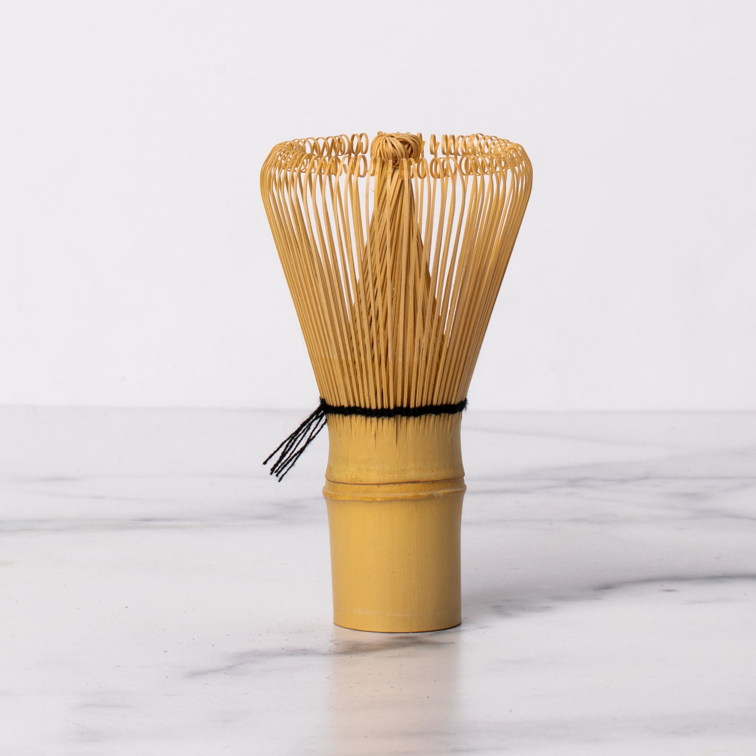 Bamboo matcha whisk with black thread.