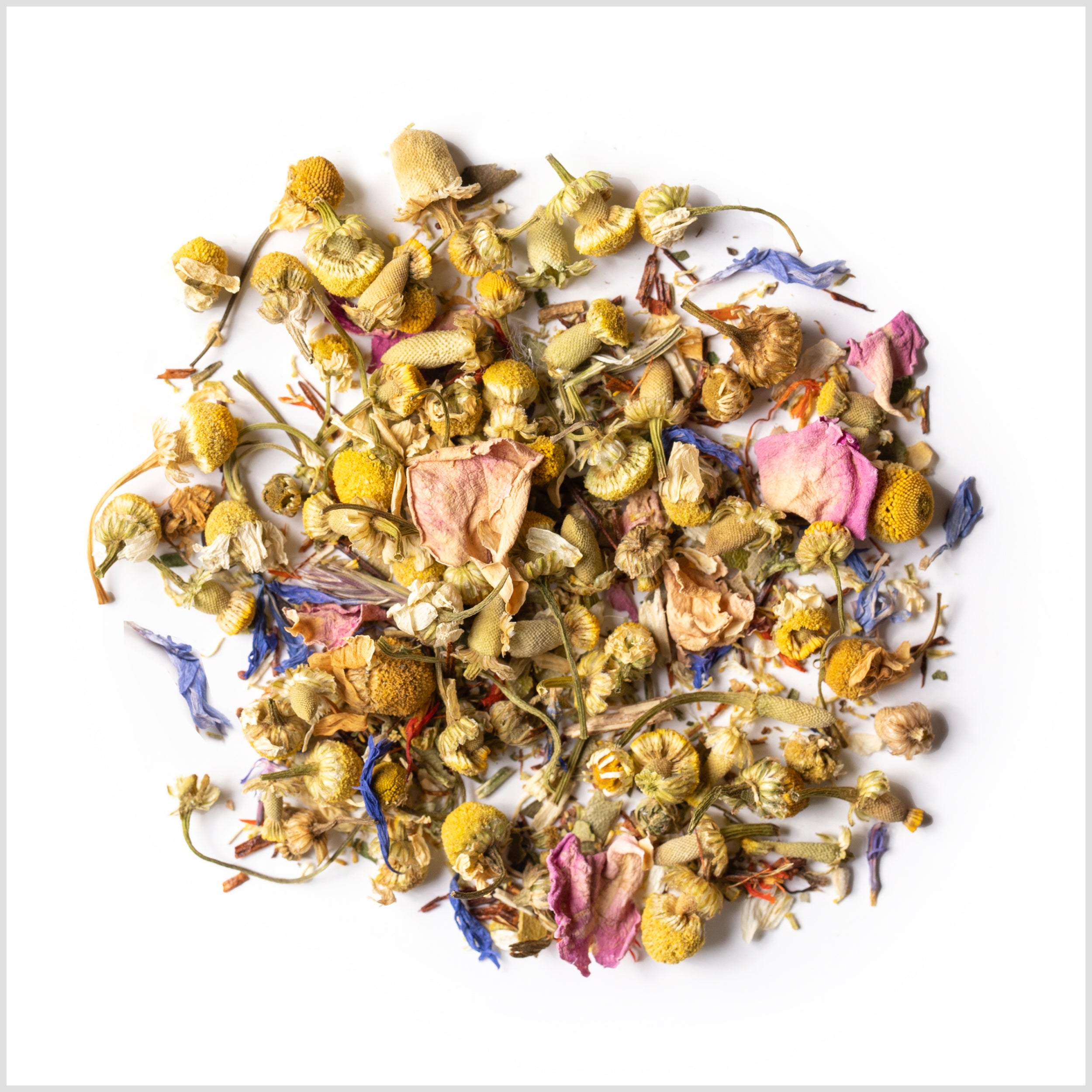 Circular pile of loose-leaf Meadow herbal infusion featuring yellow chamomile buds, pink rose petals and blue cyani flowers.
