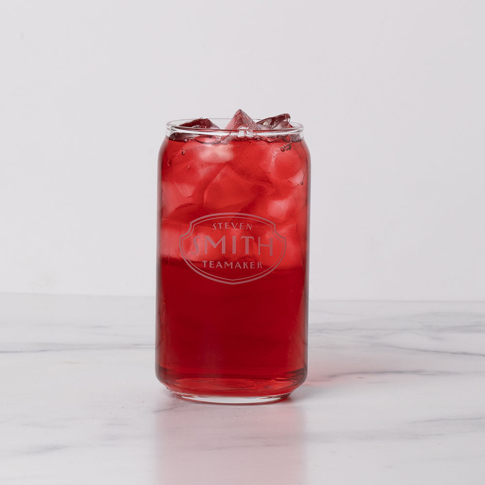 Rounded can shapped glass filled with red iced tea on a marble background.
