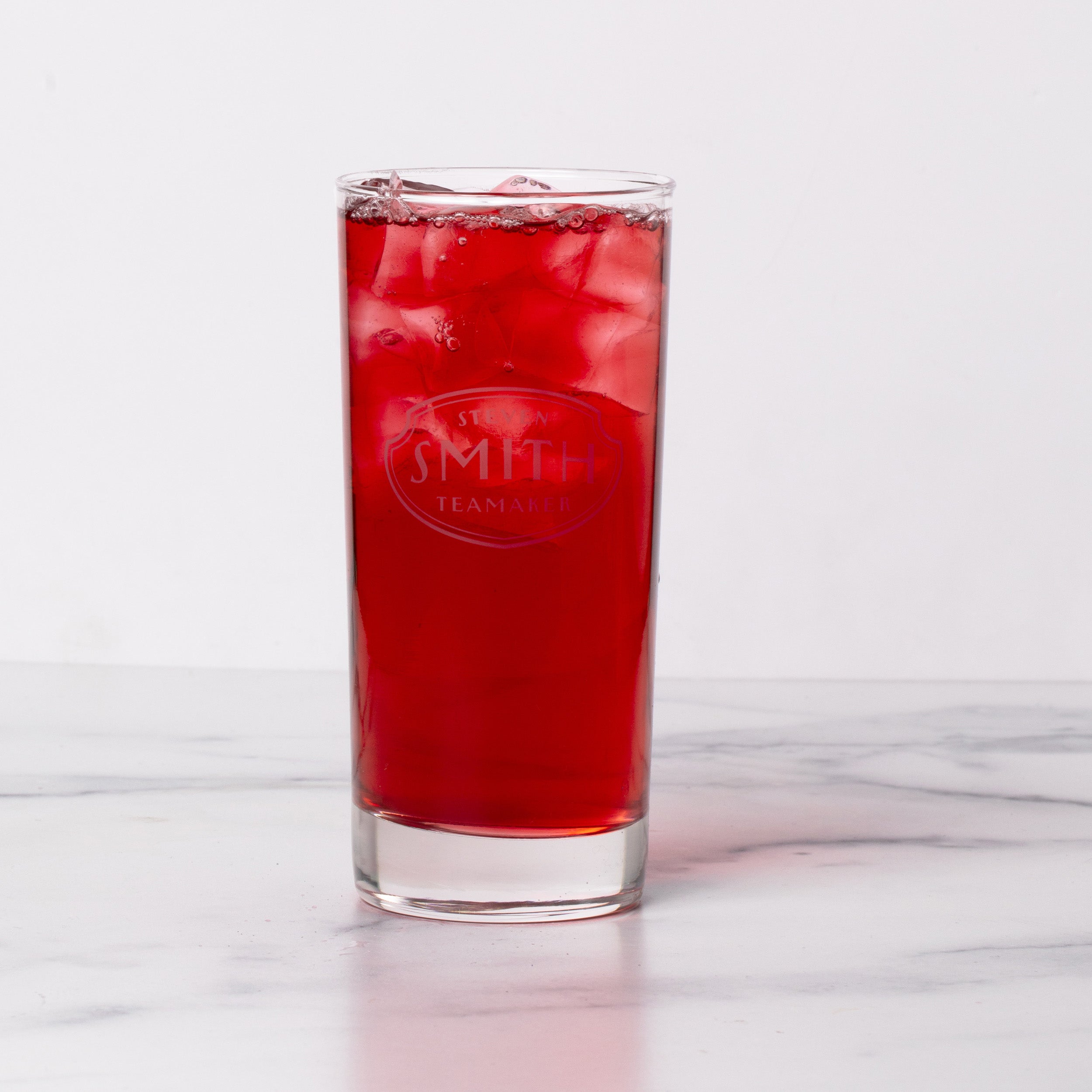 Tall collins glass branded with Smith logo shield filled with red iced tea.