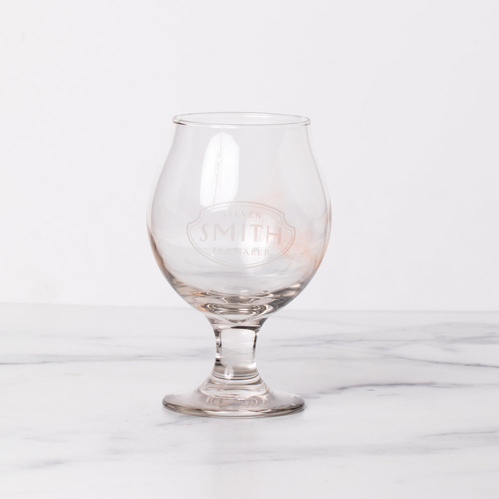 Empty snifter glass branded with Smith logo on marble table.
