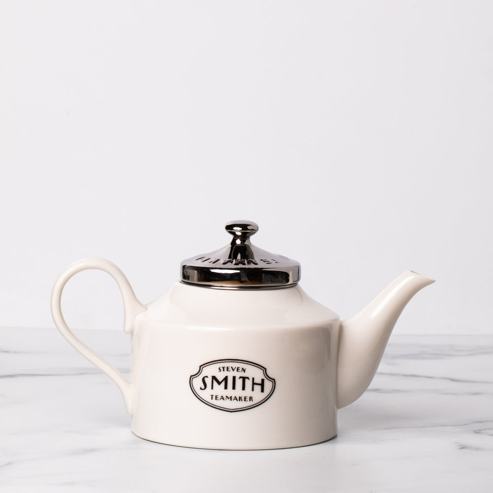 White porcelain teapot with a black logo.
