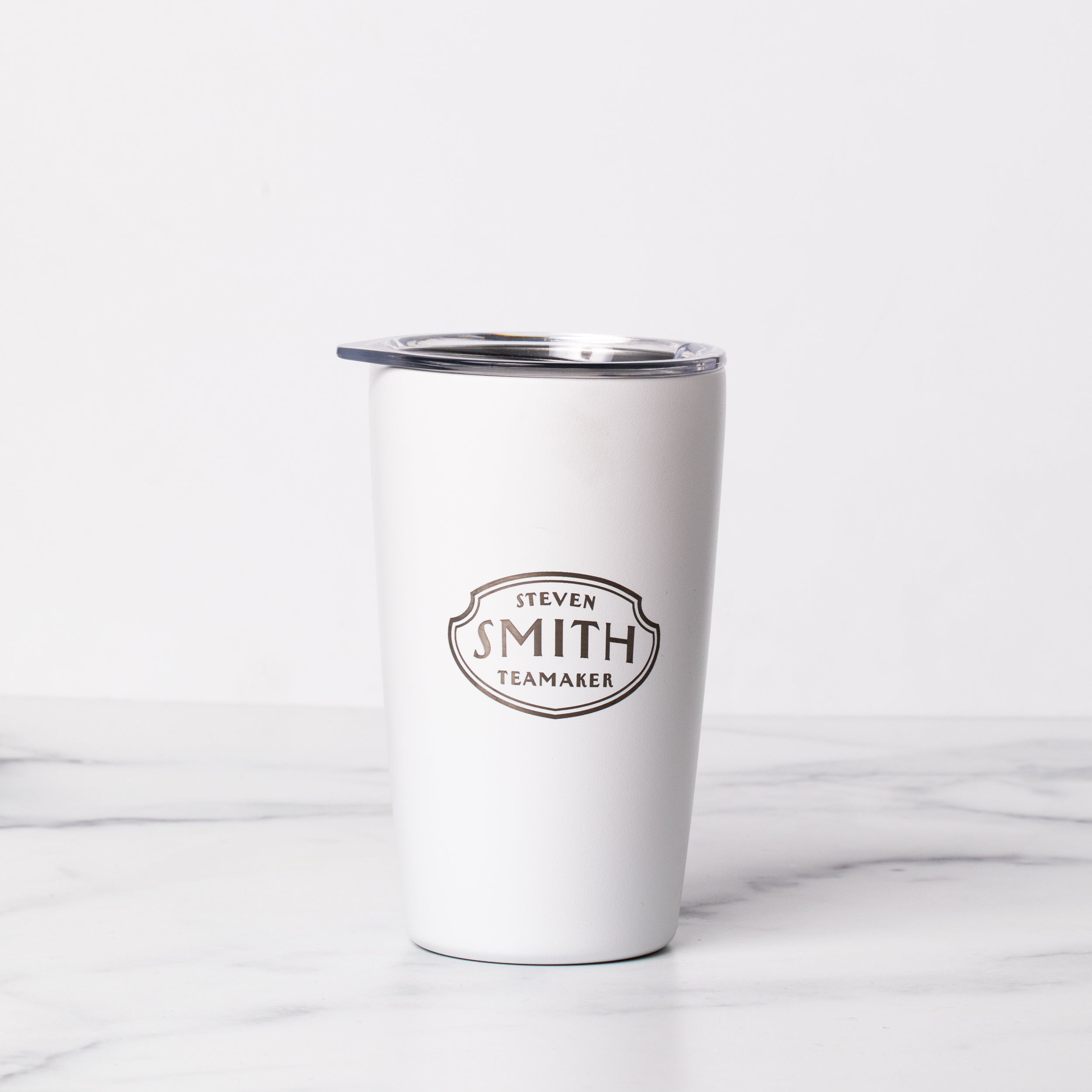 White to-go tumbler with silver etched Smith logo shield and clear top.