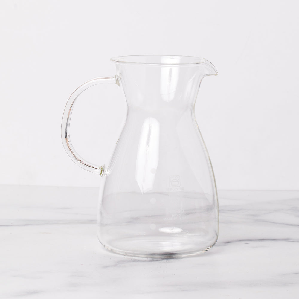 Empty glass decanter with spout on marble background.
