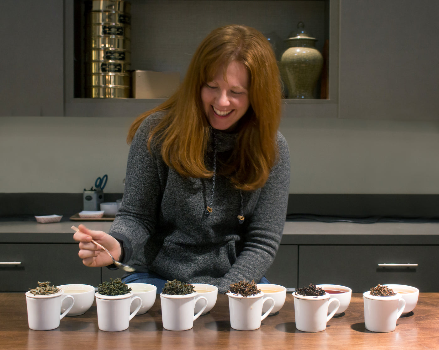 Teamaker, Sara Kaufmann, holding a spoon about to take a sip from a cup during a line tasting.