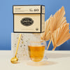 Box and glass cup of Lullaby organic wellness tea against blue background on a marble stand.