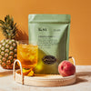 Green bag of Pineapple Green Iced Tea on a tray with full glass of iced tea.