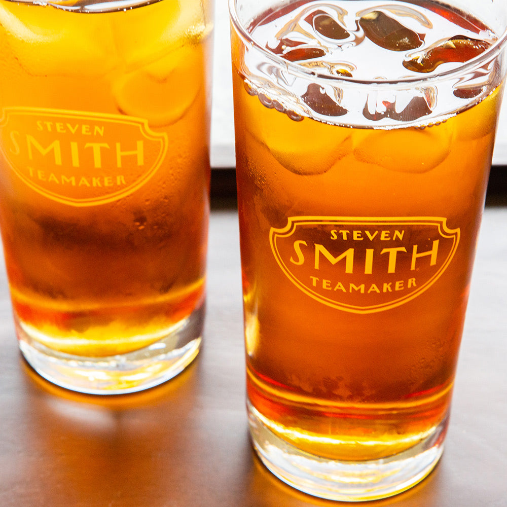Two tall collins glasses branded with Smith logo shield filled with light brown iced tea.
