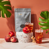 Black bag filled with 10 sachets of Ginger Peach iced tea against orange background.