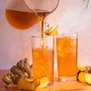 A pitcher pouring into a glass of Ginger Peach iced tea.