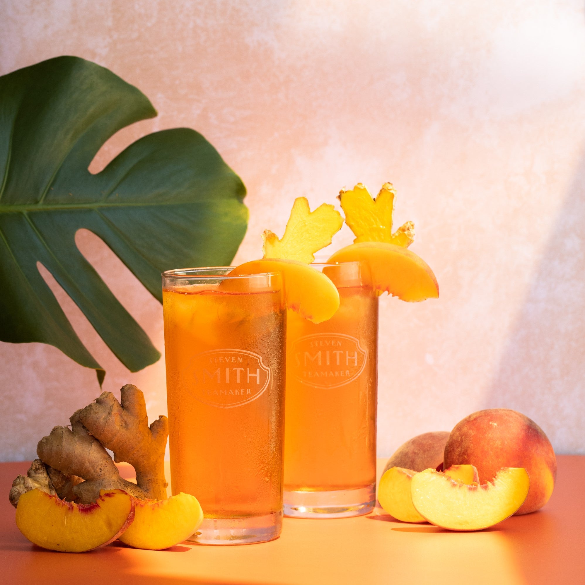Two glasses of Ginger Peach iced tea against orange background.