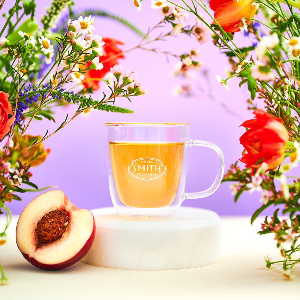 Glass cup filled with Jasmine Nectar green tea surrounded by flowers.