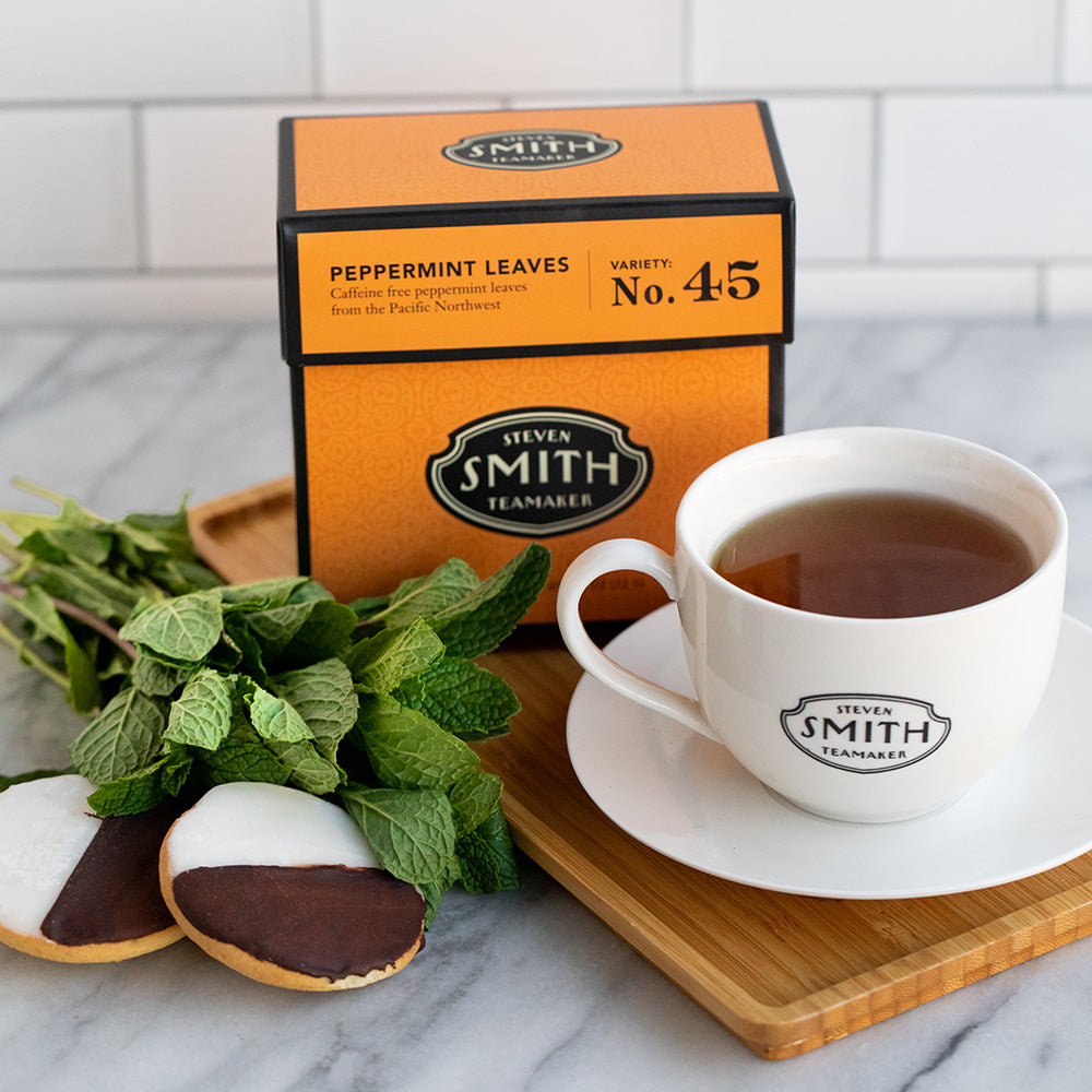 Kitchen counter  with orange box of Peppermint tea next to a white cup filled with tea.