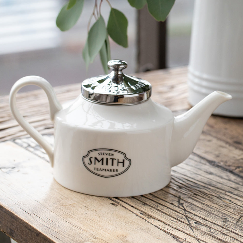 Porcelain teapot with Black smith logo and silver lid.