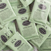 A pile of overwrapped sachets of Spring Greens green tea.
