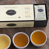 Cream box with black trim slighly open to reveal sachts of teas inside.