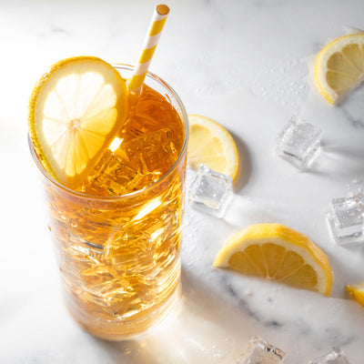 Glass of iced tea with lemon garnish filled with ice.