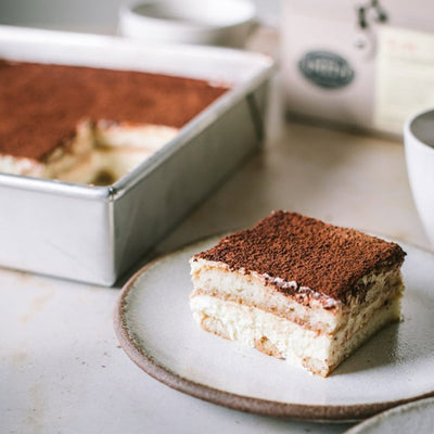 Slice of tiramisu covered chocolate powder.