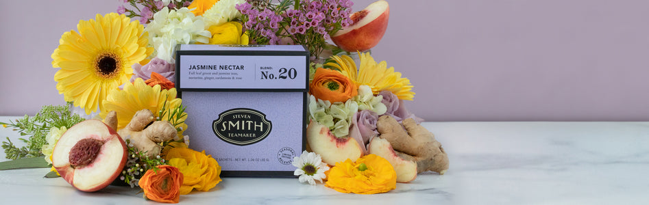 Box of Jasmine Nectar surrounded by spring flowers, peaches and ginger.