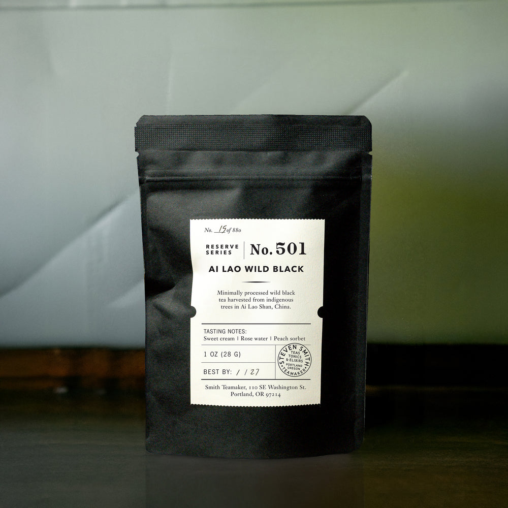 Black bag of Ai Lao Wild Black tea with intricate label including tasting notes and information about the tea.