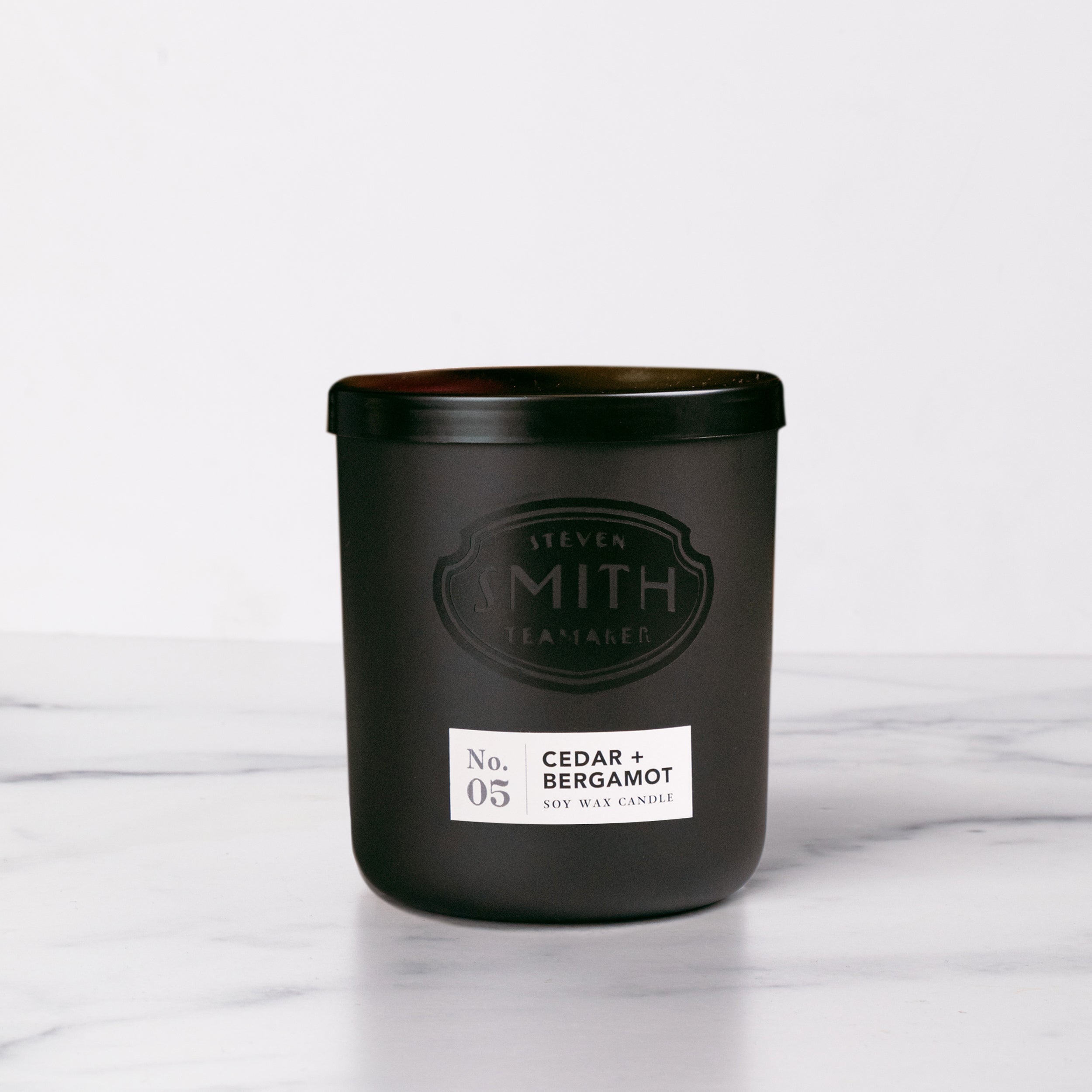 Black candle with lid, Smith logo and white label.