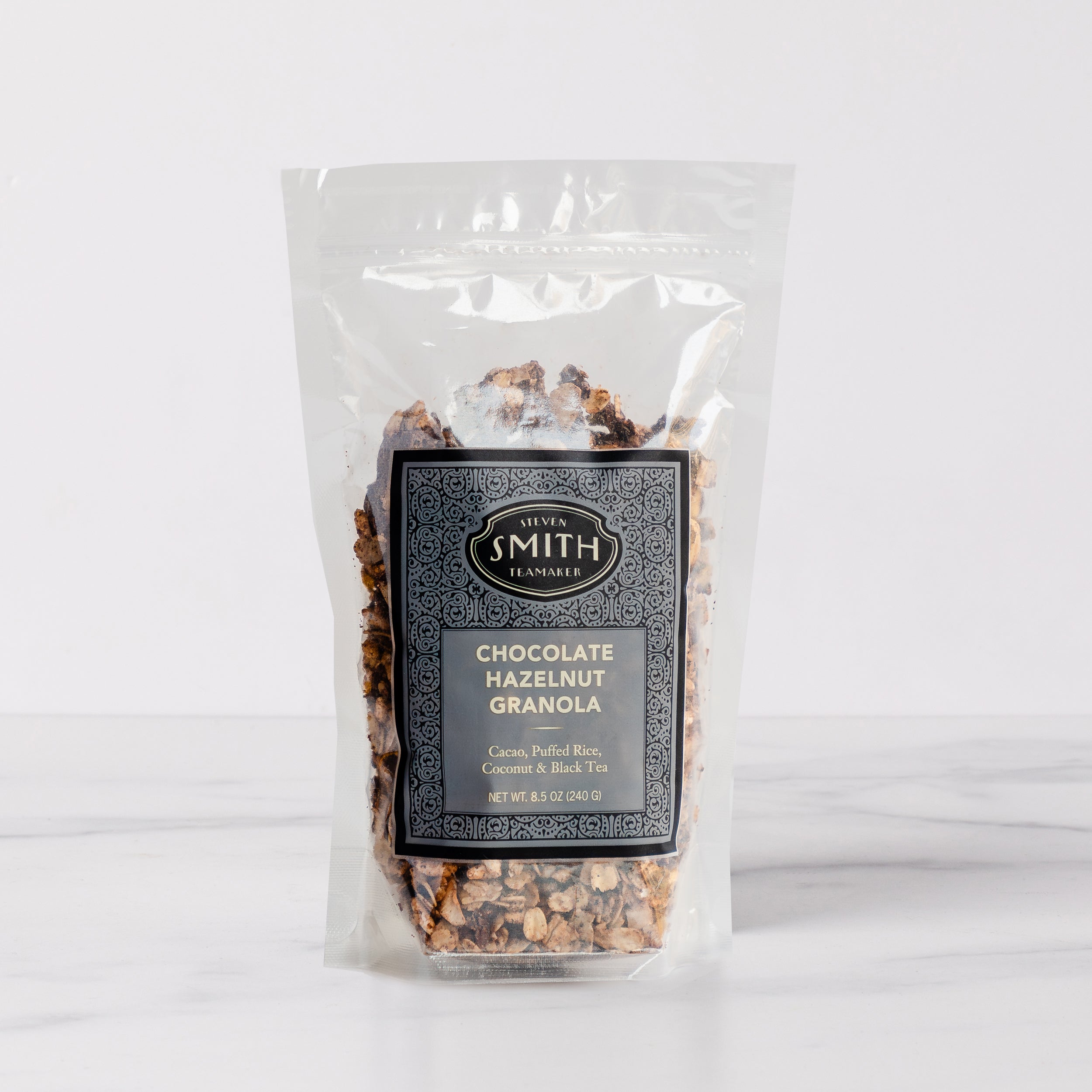 Clear bag with a label filled with tea granola on marble table..