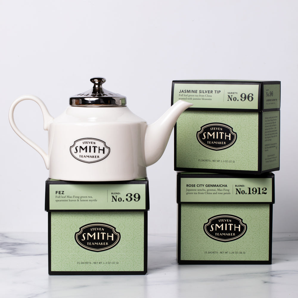 Three cartons of green tea with a white porcelain teapot.