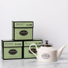 Three cartons of green tea with a white porcelain teapot.