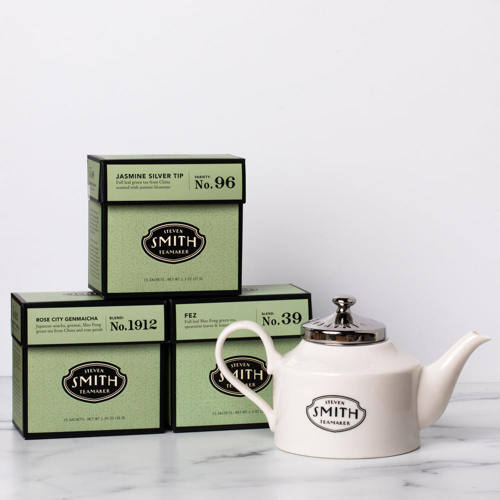 Three cartons of green tea with a white porcelain teapot.