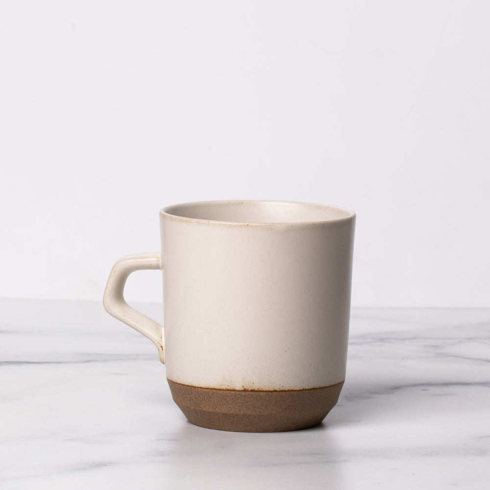 White ceramic mug with a handle on marble background.