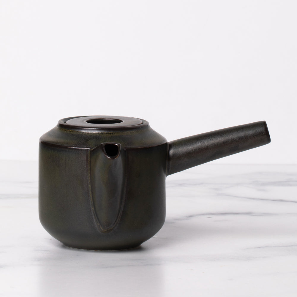 Black lidded teapot with spout and long handle.