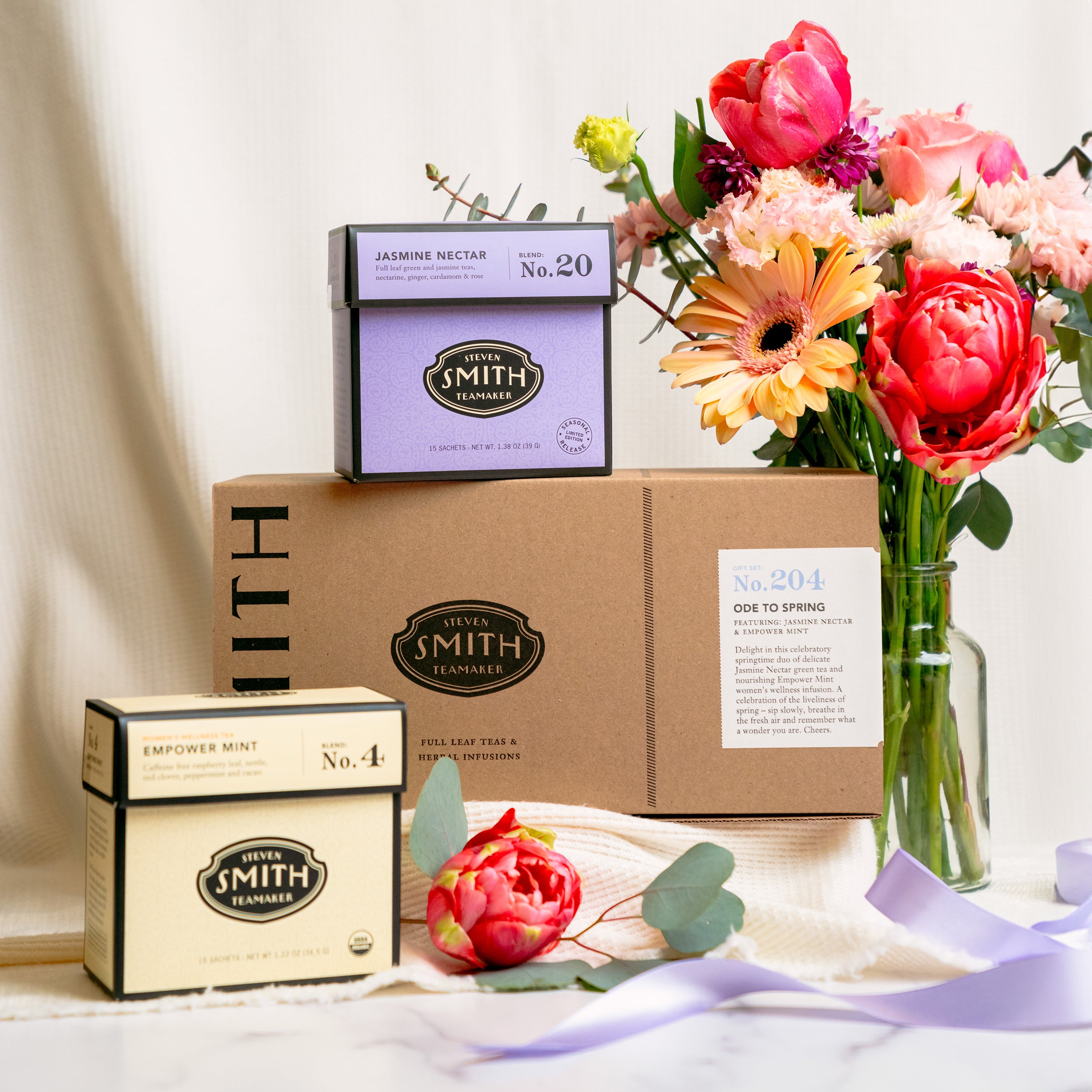 Gift box with Jasmine Nectar and Empower Mint with vase of pink flowers.