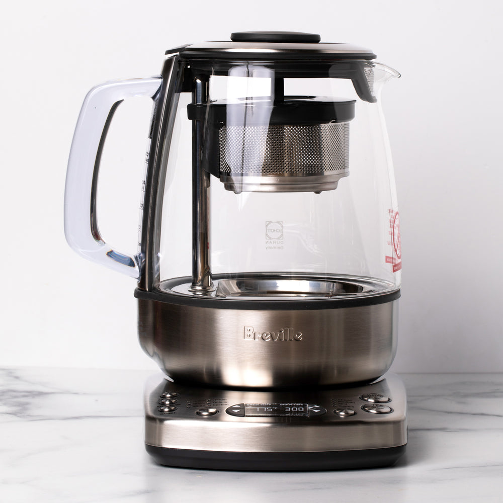 Clear electric kettle with silver handle and silver electric base.