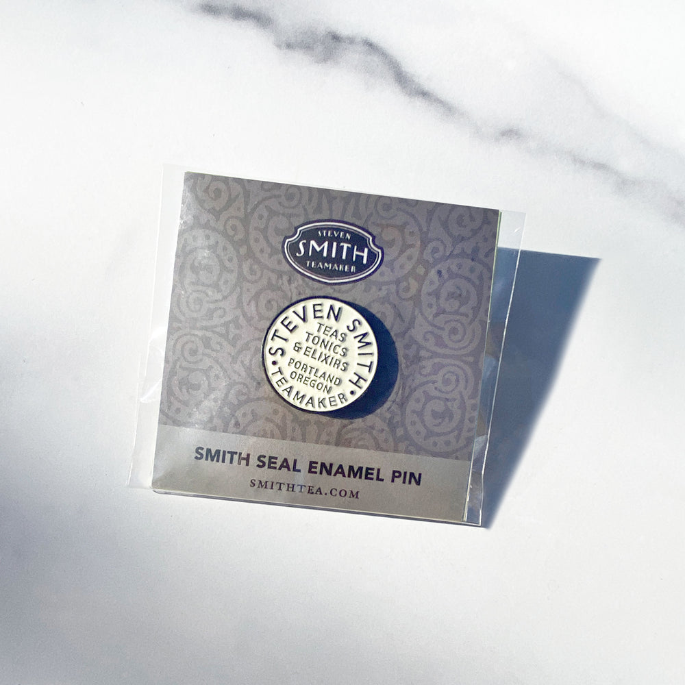 Smith Teamaker seal enamel pin with inscribed text "Steven Smith Teamaker, Teas, Tonics & Elixirs, Portland Oregon" on a grey card with text "Smith Seal Enamel Pin".
