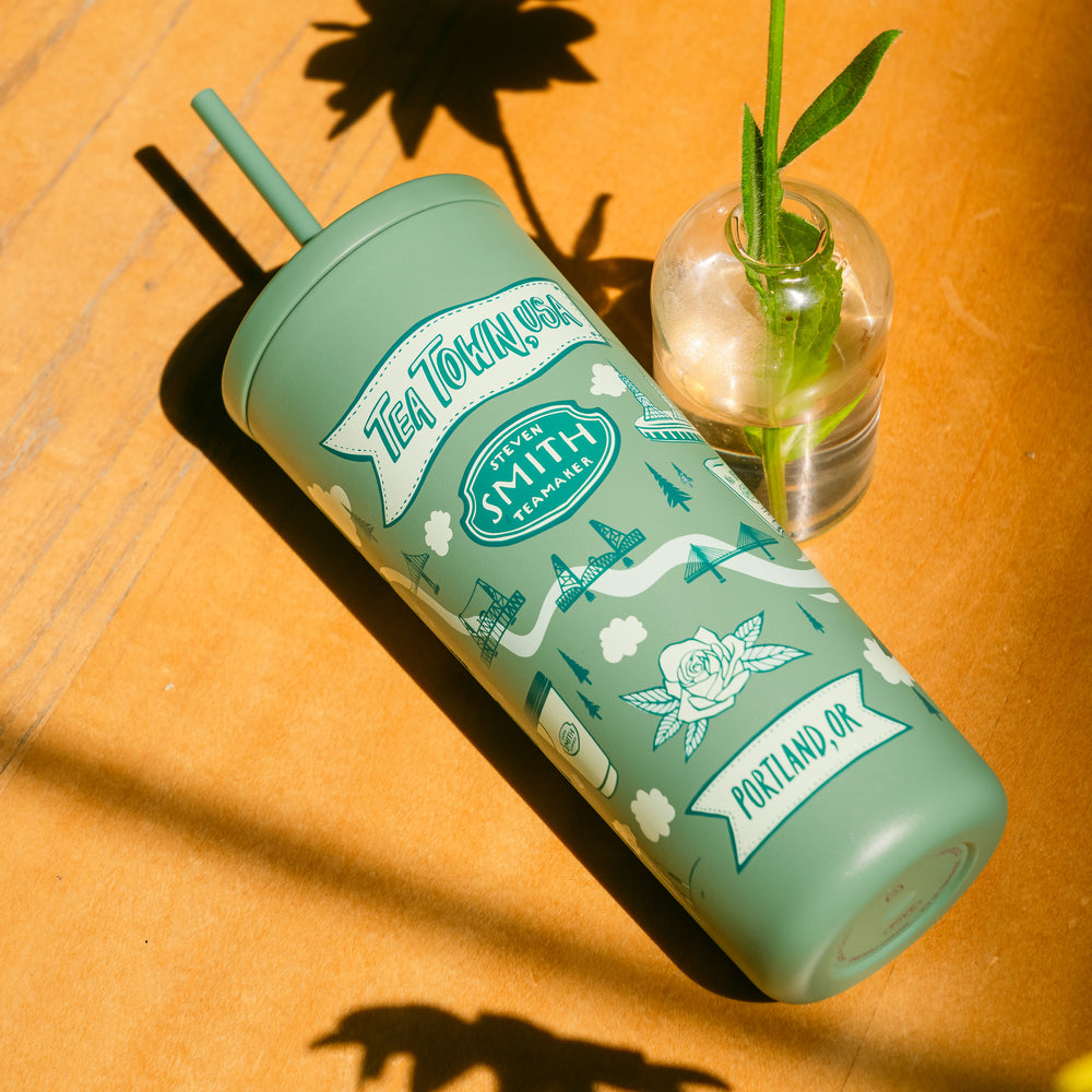 Green tumbler with 'Tea Town' design on a wooden surface