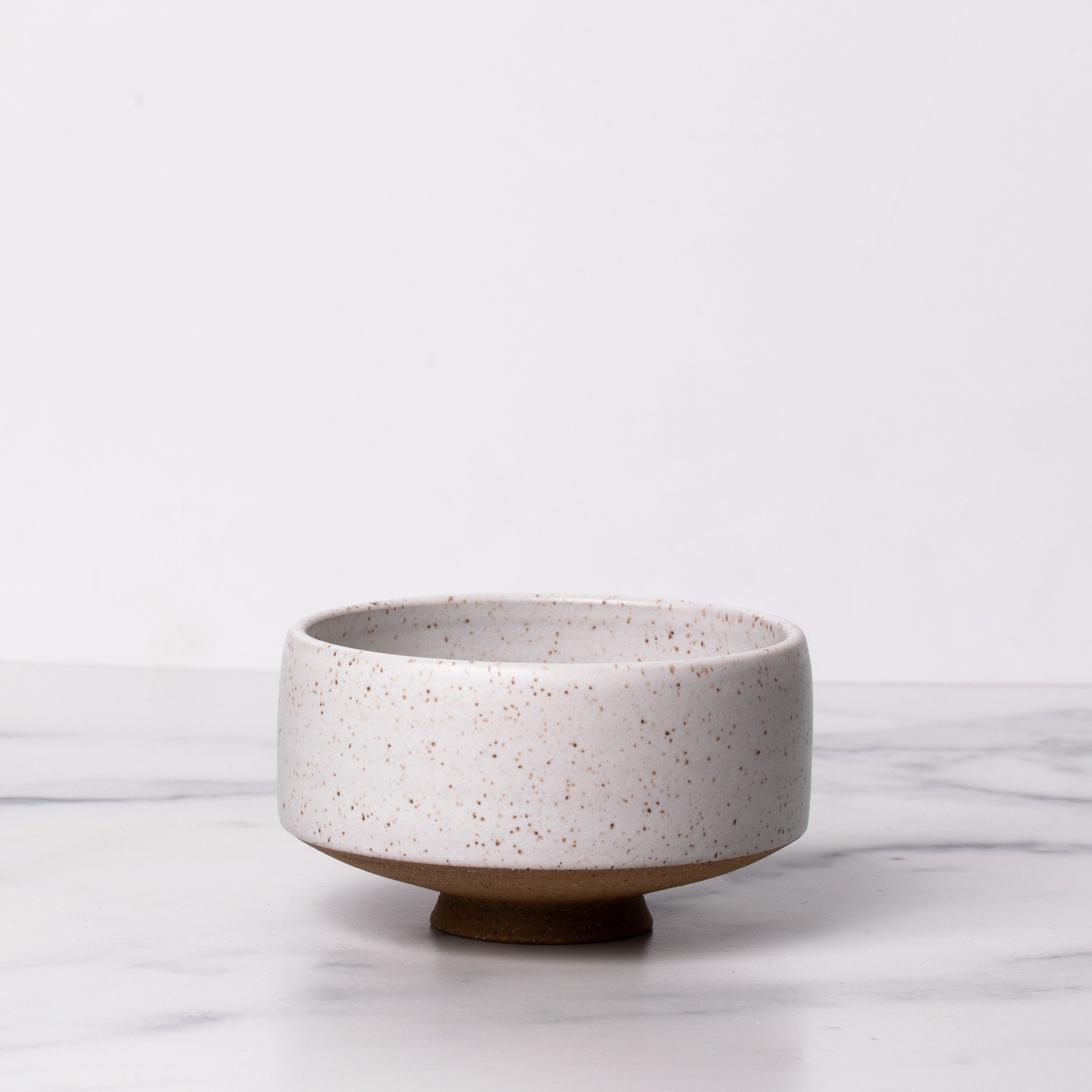 White ceramic bowl on marble background.