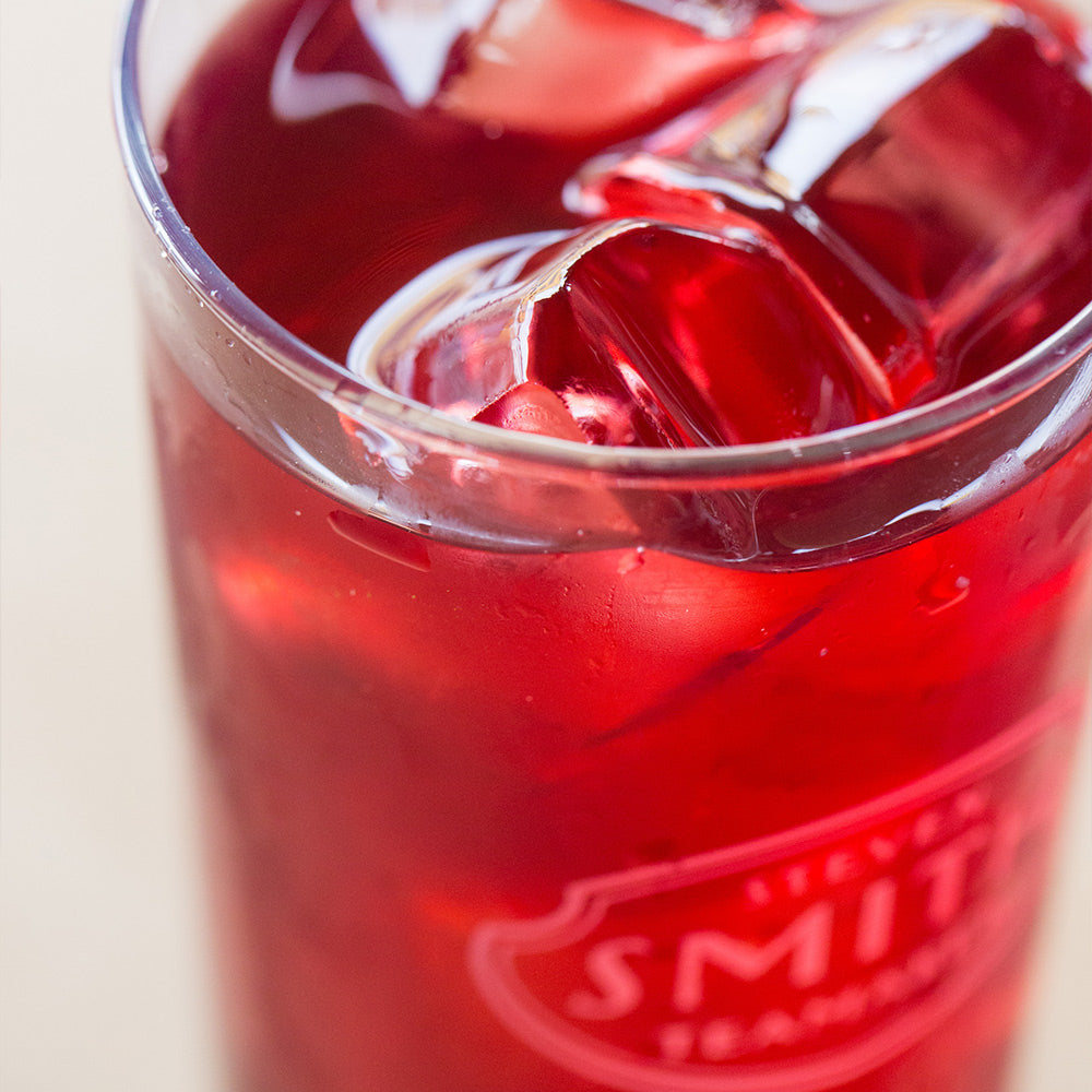 Tall collins glass branded with Smith logo shield filled with red iced tea.