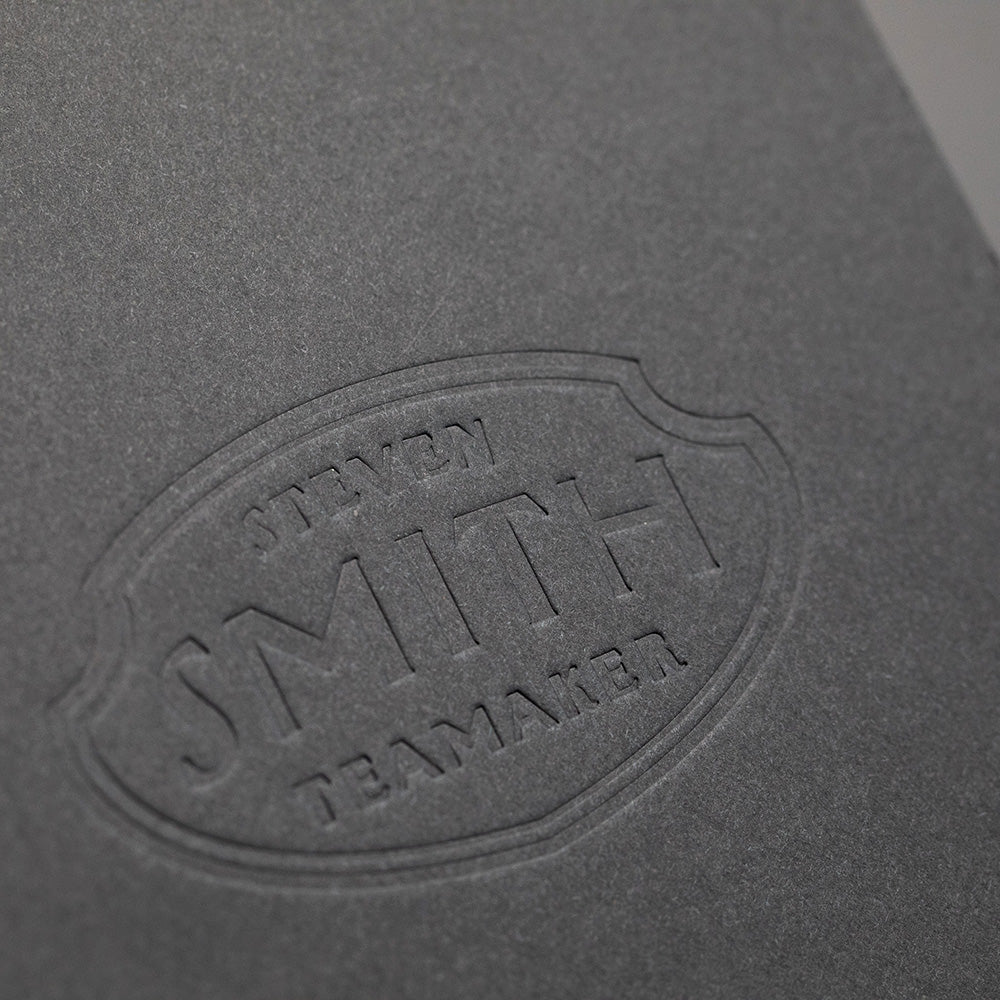 Embossed Smith shield logo on black paper.