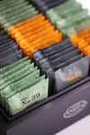 Green, black and orange sachets standing up inside black box.