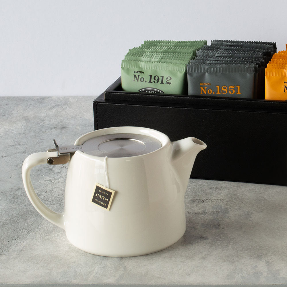 White ceramic teapot with stainless steel top on a marble table.