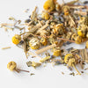 Pile of loose chamomile buds, lemongrass, and lavender on white background.